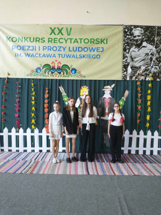 grupa uczennic w konkursie recytatorskim w tle kolorowa dekoracja